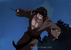 Jine rushes toward the camera, slanted to the right, with a demonic grin on his face.